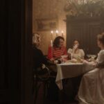 Reenactments - Group of Men and Women in Costumes Sitting by the Table