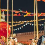 Street Fairs - Festive merry go round with carnival horses on Red Square against blurred Kremlin during New Year holidays in evening