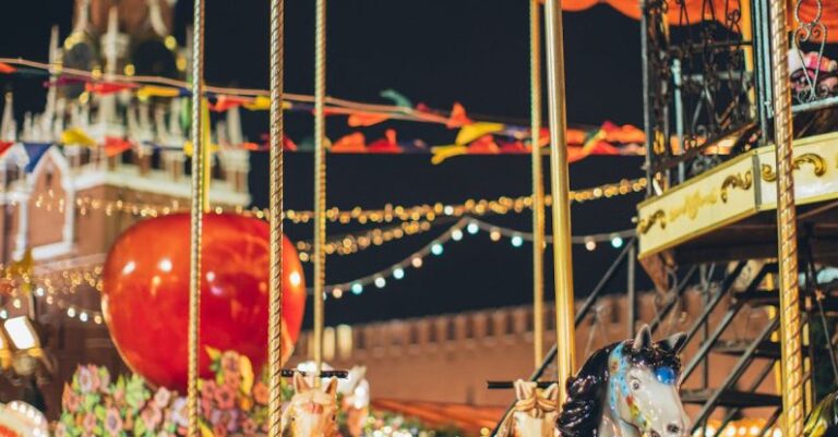 Street Fairs - Festive merry go round with carnival horses on Red Square against blurred Kremlin during New Year holidays in evening