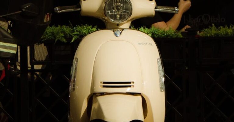 Urban Parks - A white moped parked on a sidewalk next to a building