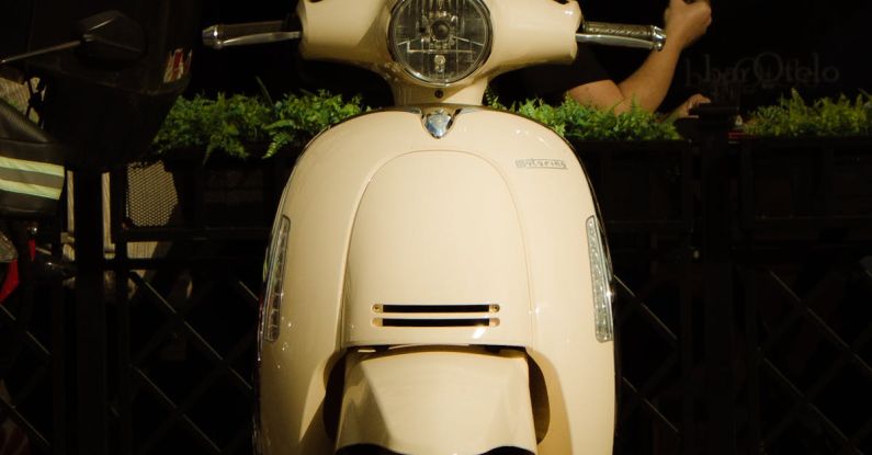 Urban Parks - A white moped parked on a sidewalk next to a building