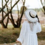 Picnic Spots - A woman in a white dress and hat is walking through the woods