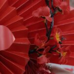Art Festivals - A person holding a red paper fan with red flowers